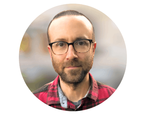 Dan Bivins outside smiling wearing glasses and red and black flannel